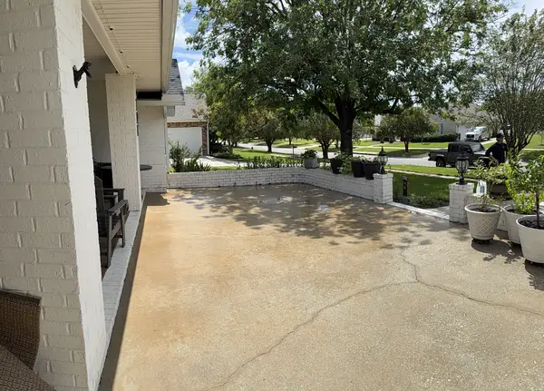 Concrete patio beside a white brick home after pressure washing
