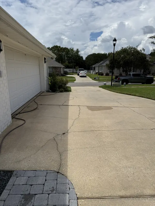 Clean concrete driveway beside a white garage after pressure washing