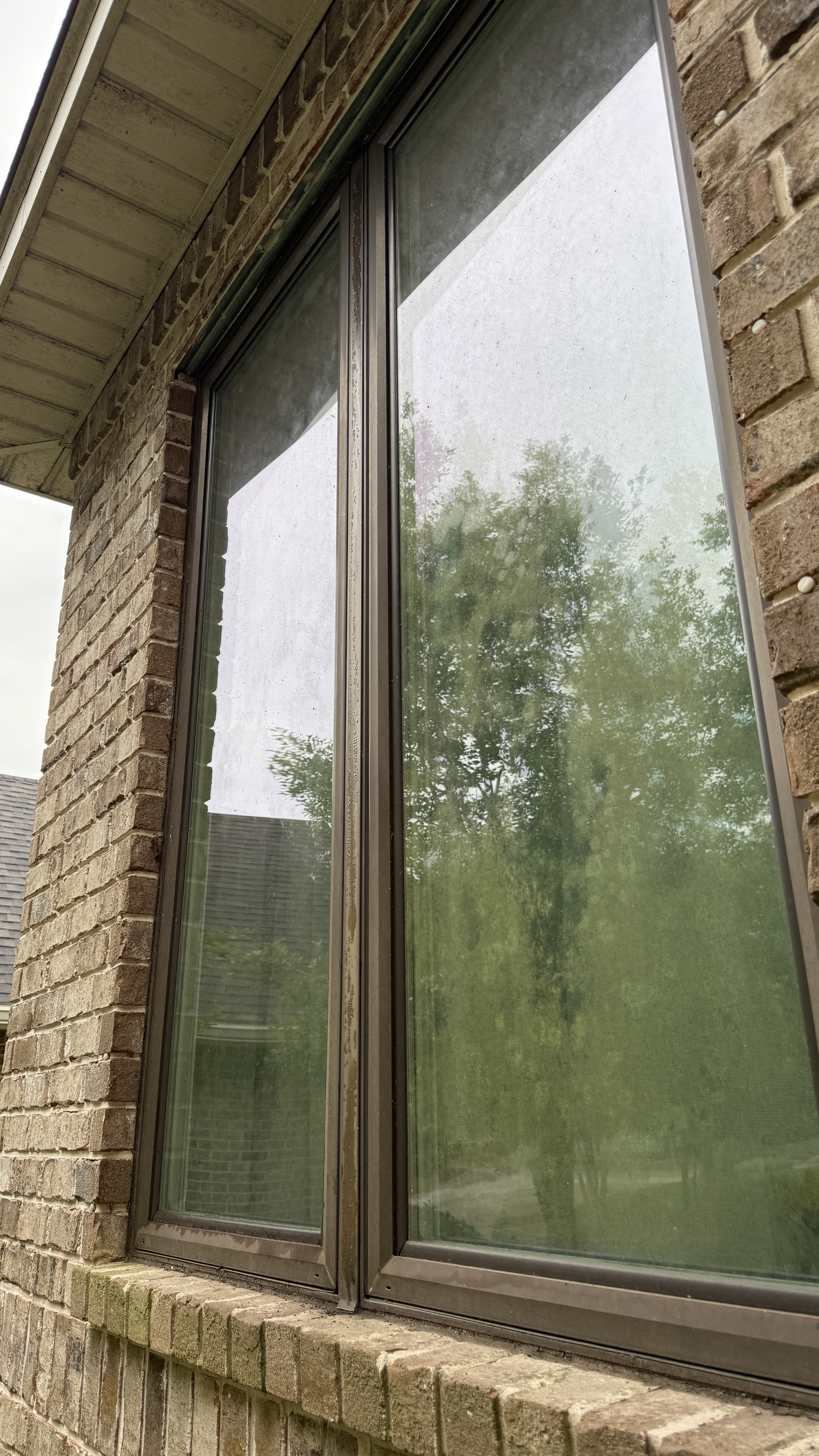 Windows with dirt and buildup before window washing at a brick home in Pensacola Florida
